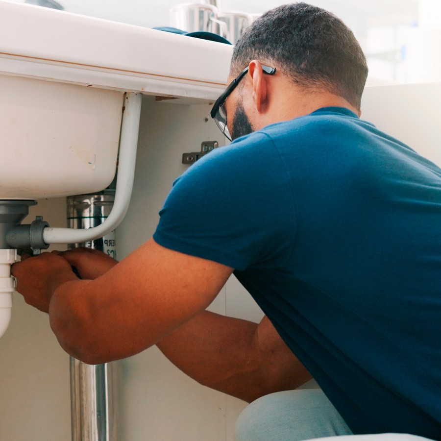 Plumber fixing the kitchen sink drain Image of a Plumber fixing the kitchen sink drain
